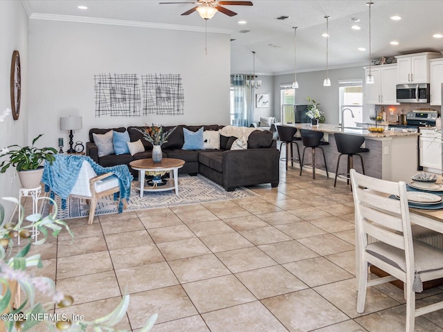 tiled living room with ceiling fan, sink, and ornamental molding