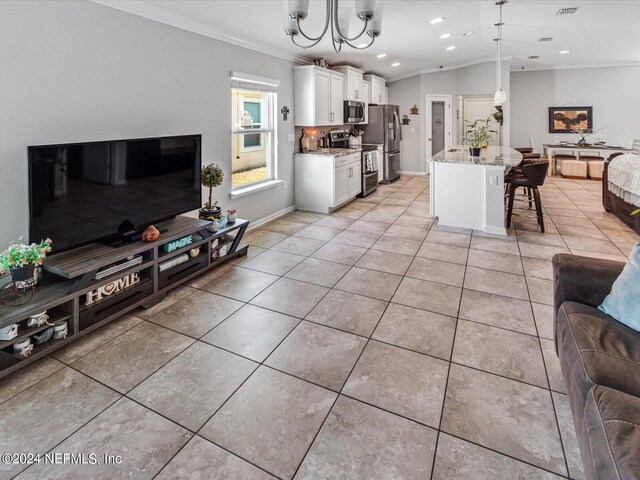 tiled living room featuring a notable chandelier, ornamental molding, and lofted ceiling