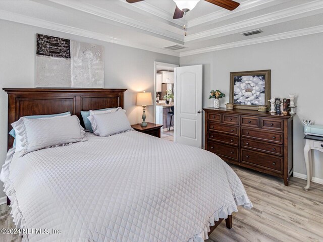 bedroom featuring ceiling fan, a raised ceiling, crown molding, and light wood-type flooring