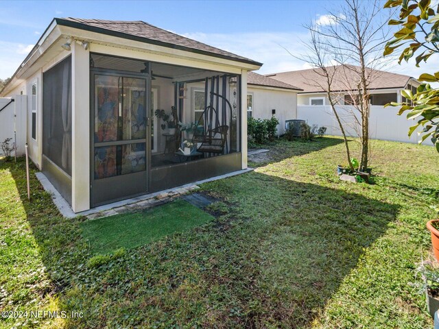 rear view of property featuring a sunroom and a yard