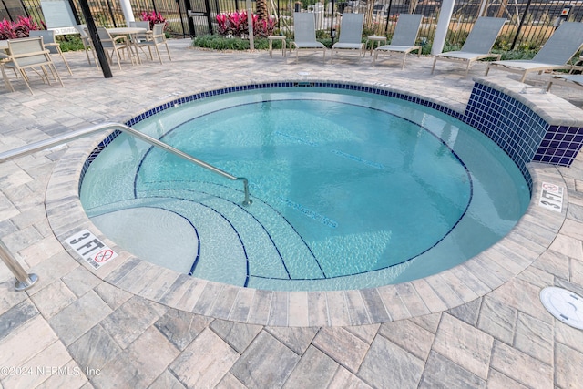 view of swimming pool with a patio, fence, and a hot tub