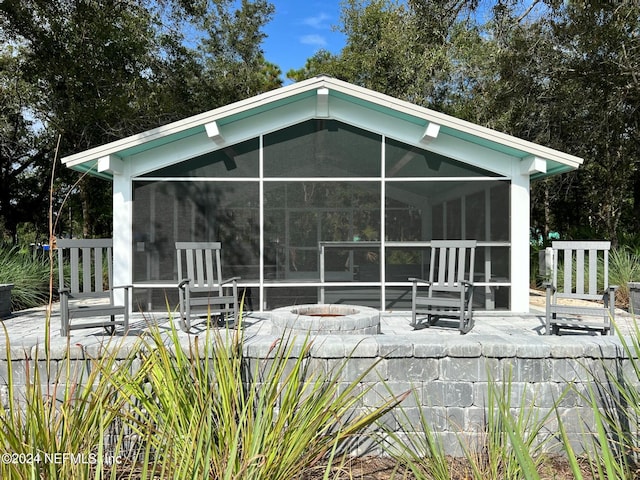 back of house featuring a sunroom, a patio area, and a fire pit