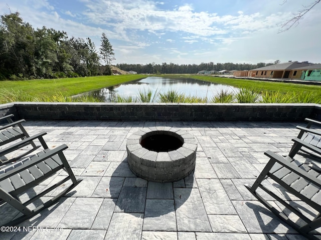 view of patio with an outdoor fire pit and a water view