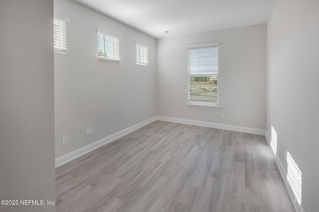 spare room with baseboards, visible vents, and light wood finished floors