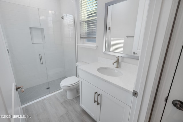 bathroom with a stall shower, vanity, and toilet