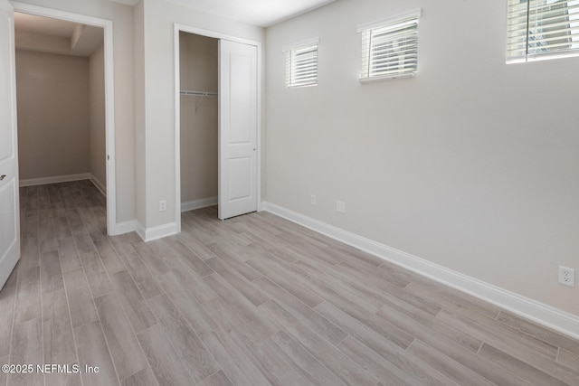 unfurnished bedroom featuring light wood-style floors, a closet, and baseboards