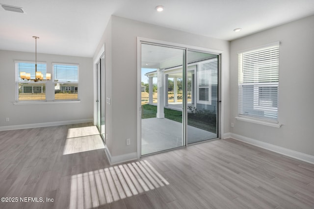 entryway with an inviting chandelier, plenty of natural light, visible vents, and wood finished floors