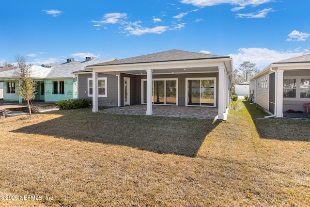 rear view of house featuring a shingled roof and a lawn