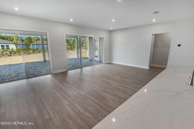 unfurnished living room featuring baseboards, visible vents, dark wood-style flooring, and recessed lighting