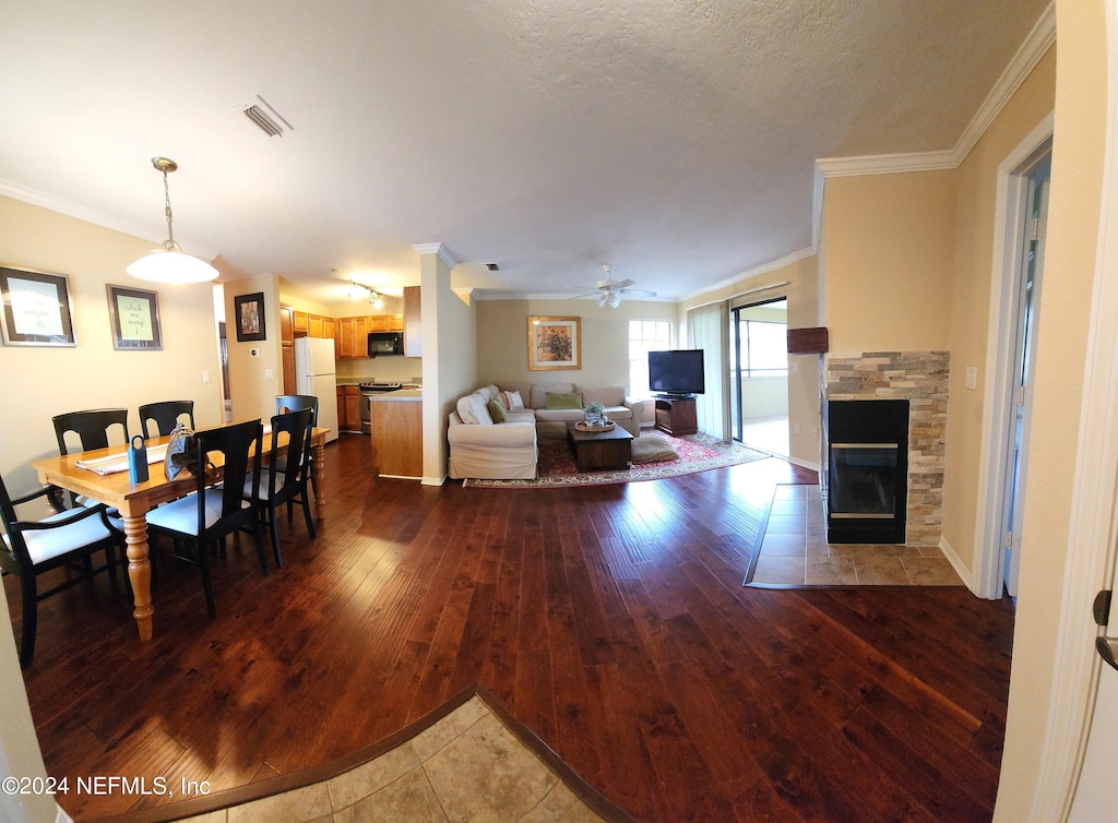 living room featuring crown molding, hardwood / wood-style floors, ceiling fan, and a fireplace