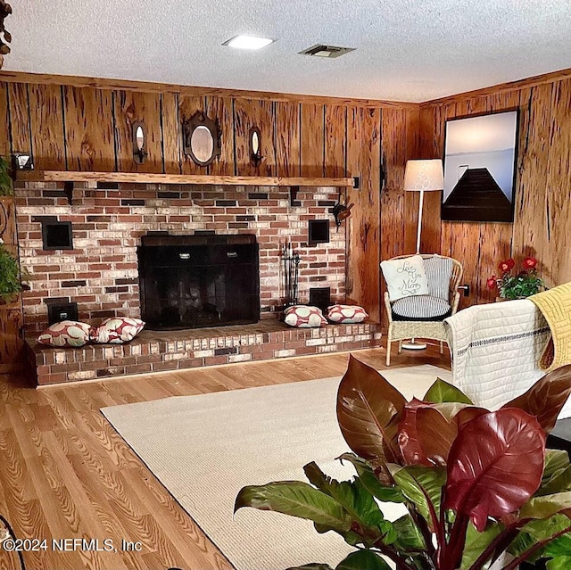 living room with a brick fireplace, a textured ceiling, wood walls, and light wood-type flooring