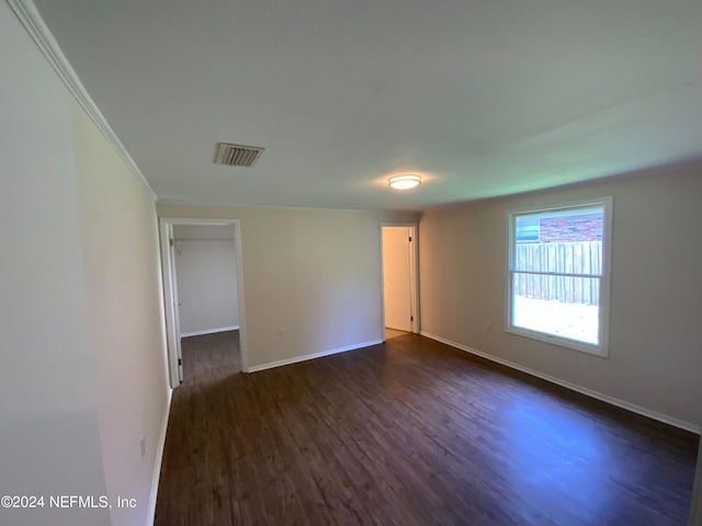 empty room with dark wood-type flooring and crown molding