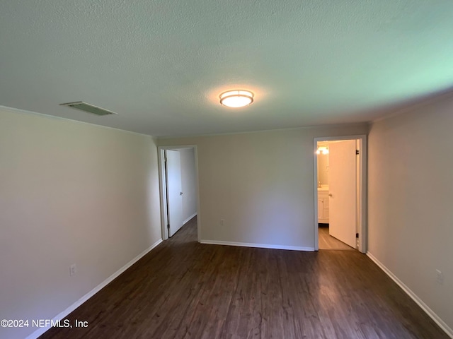 empty room featuring a textured ceiling and dark hardwood / wood-style flooring