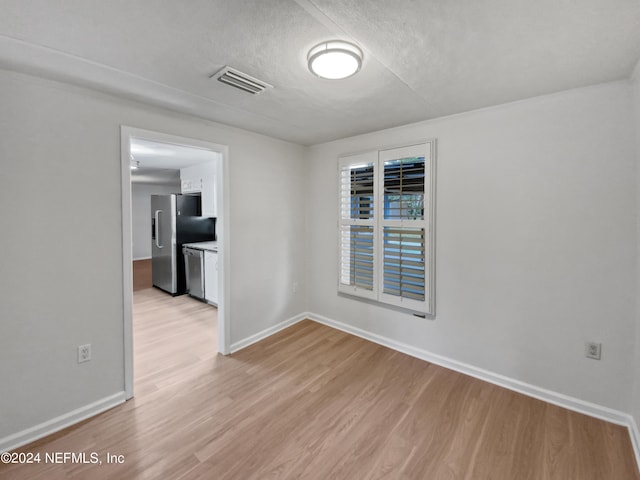 empty room with a textured ceiling and light wood-type flooring