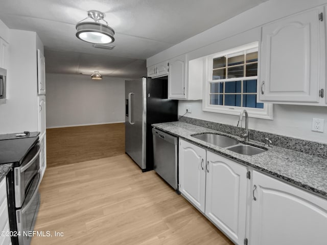 kitchen featuring appliances with stainless steel finishes, white cabinetry, sink, light stone countertops, and light hardwood / wood-style flooring