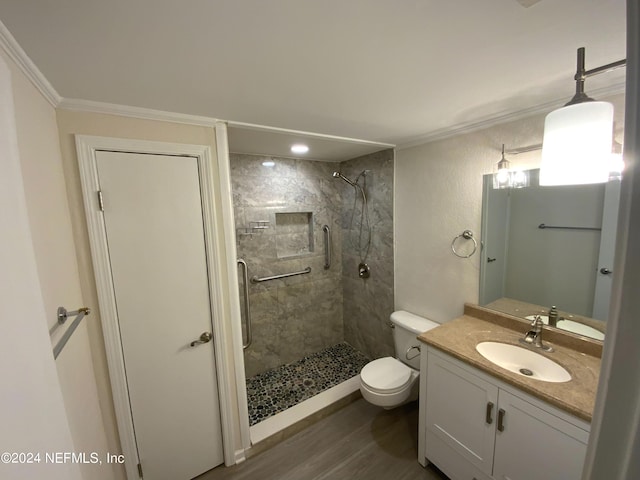 bathroom with toilet, a tile shower, ornamental molding, vanity, and hardwood / wood-style flooring