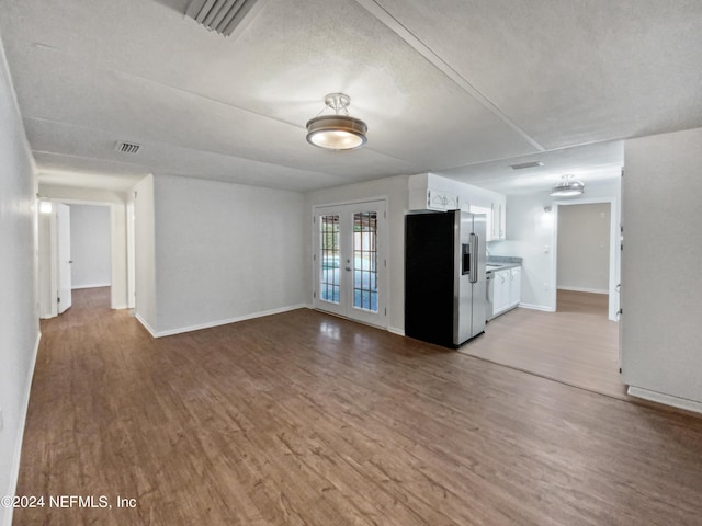 unfurnished living room featuring french doors, a textured ceiling, and light hardwood / wood-style flooring