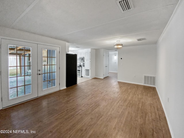 unfurnished living room with hardwood / wood-style floors and french doors