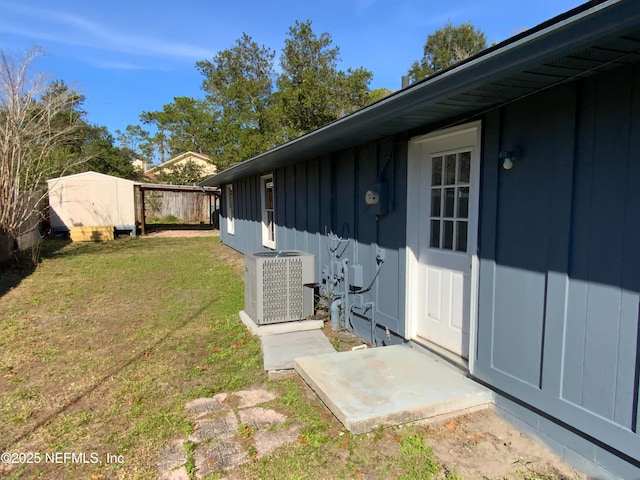 view of exterior entry with cooling unit and a yard