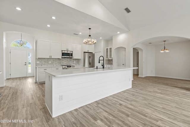 kitchen featuring a spacious island, white cabinetry, light hardwood / wood-style flooring, stainless steel appliances, and decorative light fixtures