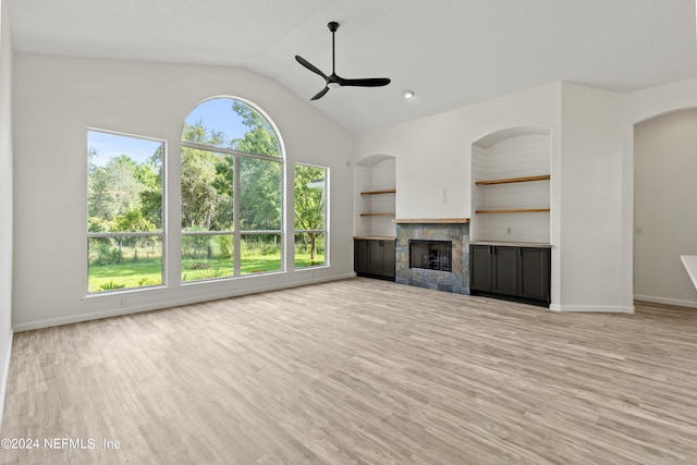 unfurnished living room featuring light hardwood / wood-style flooring, built in features, vaulted ceiling, and a fireplace