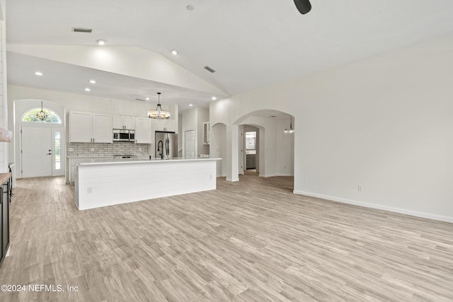 unfurnished living room featuring light hardwood / wood-style floors, a notable chandelier, and vaulted ceiling