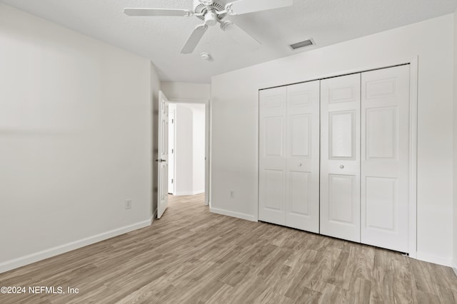 unfurnished bedroom featuring light hardwood / wood-style flooring, a textured ceiling, a closet, and ceiling fan