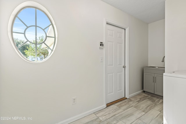 laundry area featuring washer / dryer, a textured ceiling, cabinets, and sink