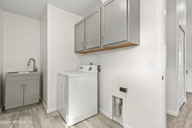 laundry room with washer / dryer, cabinets, a textured ceiling, light wood-type flooring, and sink