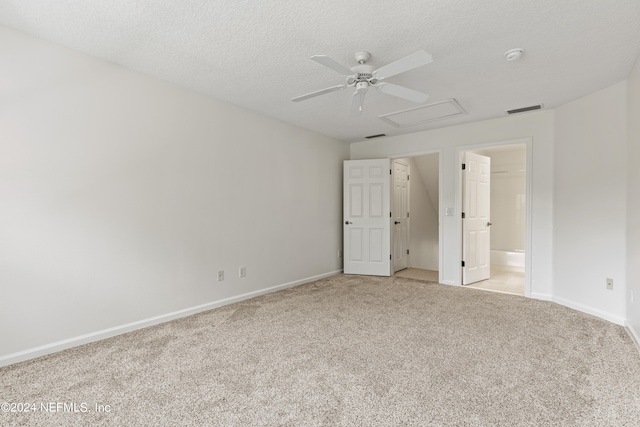 unfurnished bedroom with connected bathroom, light carpet, a textured ceiling, and ceiling fan