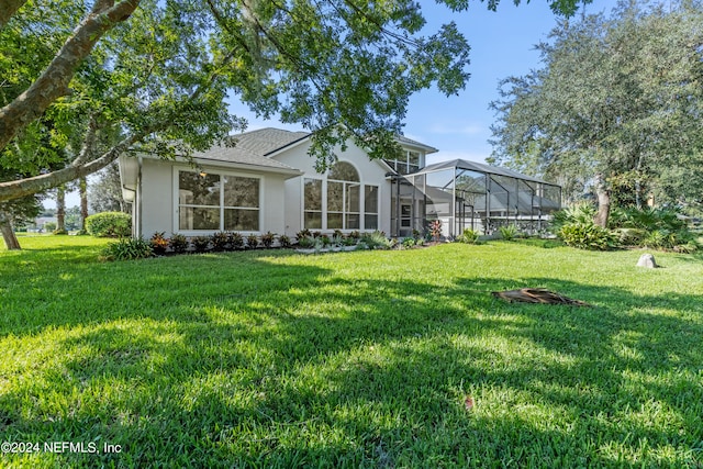 rear view of house with a yard and a lanai