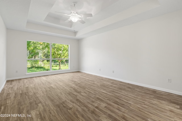 empty room featuring hardwood / wood-style floors, ceiling fan, and a raised ceiling