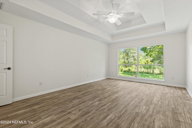 spare room featuring dark wood-type flooring, a tray ceiling, and ceiling fan