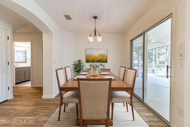 dining space featuring light hardwood / wood-style floors, a textured ceiling, and a chandelier