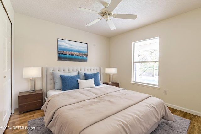 bedroom with a closet, a textured ceiling, hardwood / wood-style flooring, and ceiling fan