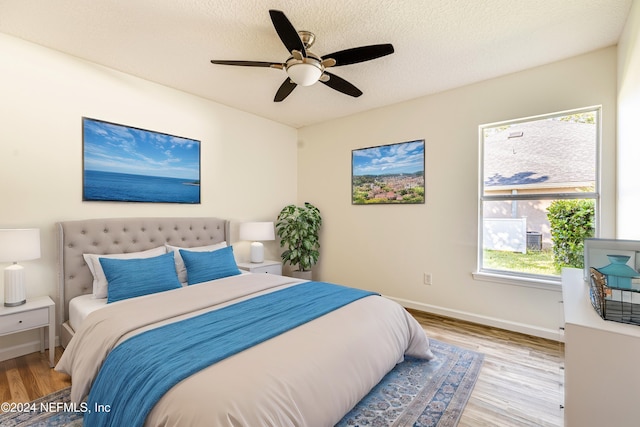 bedroom featuring light hardwood / wood-style flooring, multiple windows, and ceiling fan