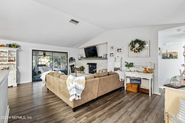 living room featuring lofted ceiling, dark wood-type flooring, and a brick fireplace