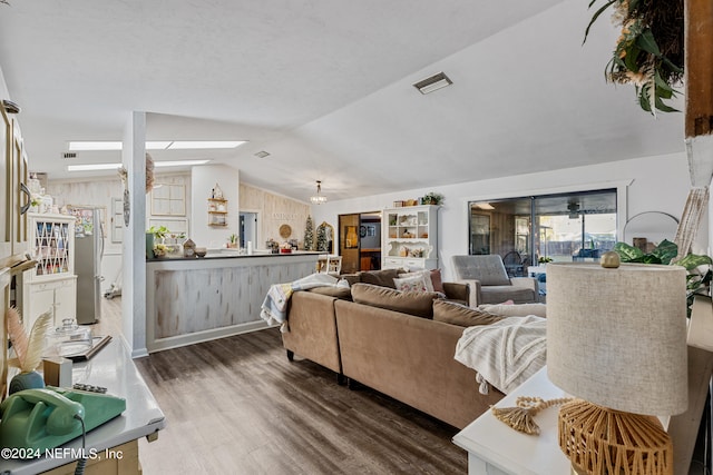 living room with vaulted ceiling with skylight and dark wood-type flooring