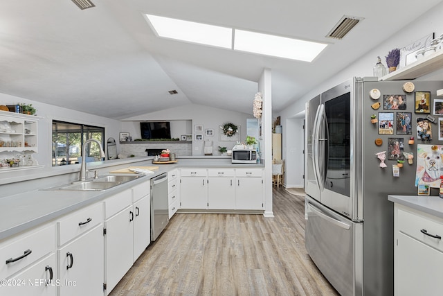 kitchen featuring vaulted ceiling with skylight, sink, appliances with stainless steel finishes, light hardwood / wood-style flooring, and white cabinetry