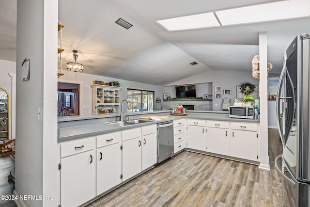 kitchen with sink, light wood-type flooring, white cabinets, appliances with stainless steel finishes, and lofted ceiling