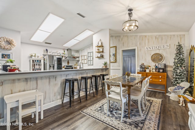 dining space featuring lofted ceiling with skylight, a notable chandelier, sink, and dark hardwood / wood-style flooring