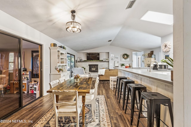 dining room featuring a notable chandelier, lofted ceiling, dark hardwood / wood-style flooring, and a fireplace