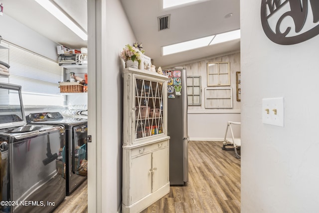 kitchen featuring hardwood / wood-style floors, lofted ceiling, and independent washer and dryer