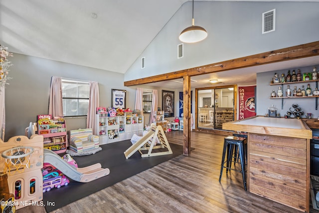 playroom with beam ceiling, high vaulted ceiling, dark wood-type flooring, and bar