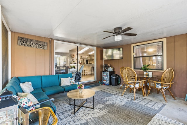 living room featuring wooden walls and ceiling fan