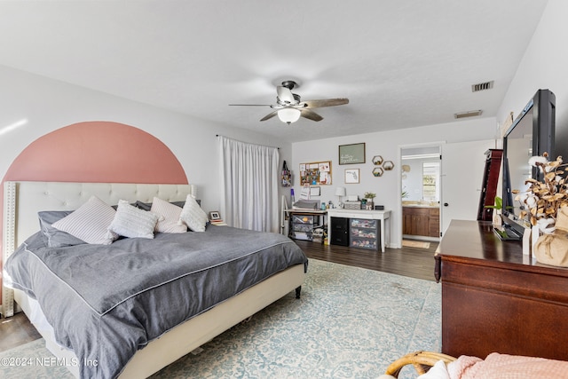 bedroom with ensuite bath, ceiling fan, and hardwood / wood-style flooring