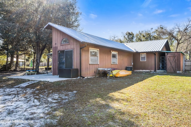 exterior space with a patio, central air condition unit, a lawn, and a shed