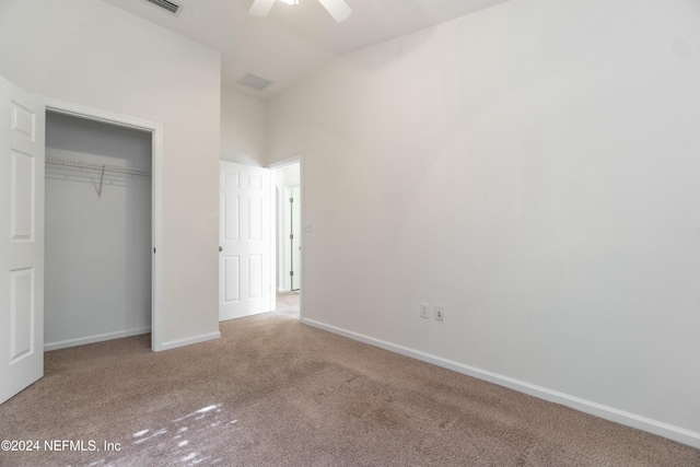 unfurnished bedroom with ceiling fan, a closet, light carpet, and vaulted ceiling