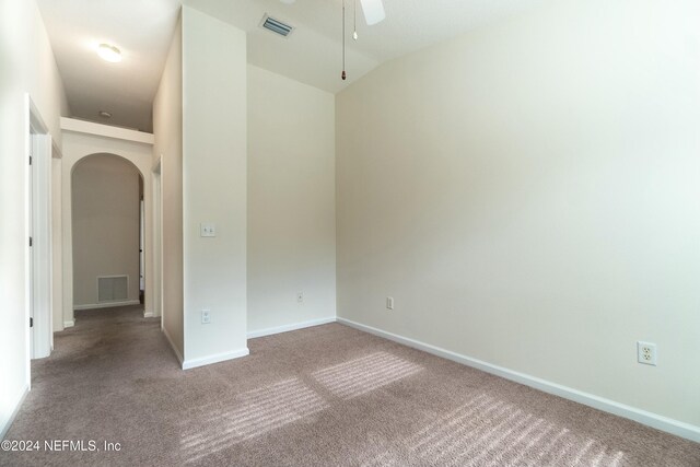 carpeted empty room with vaulted ceiling and ceiling fan