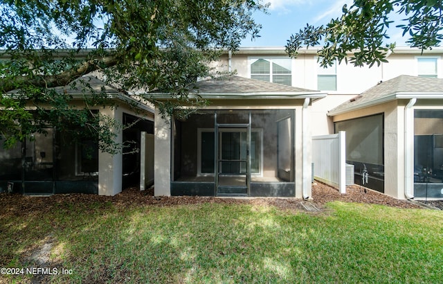 rear view of house with a yard and a sunroom